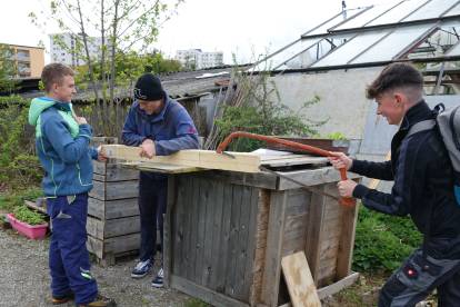 3 Männer bauen ein Kiste und sägen Holz