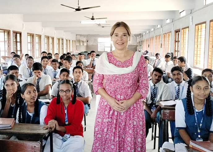 Frau steht in einer Schulklasse und lächelt in die Kamera