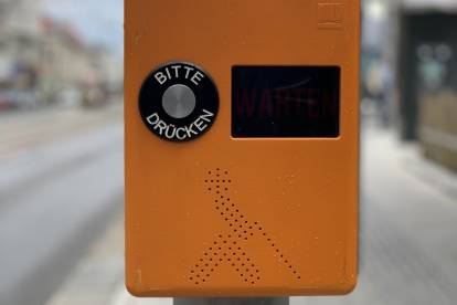 Eine orange Akustikampel von vorne fotografiert. Deutlich zu sehen ist der Knopf: BITTE DRÜCKEN.